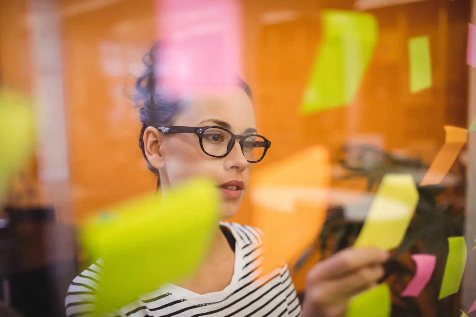 Mujer creativa organizando ideas con notas adhesivas en una agencia de publicidad moderna
